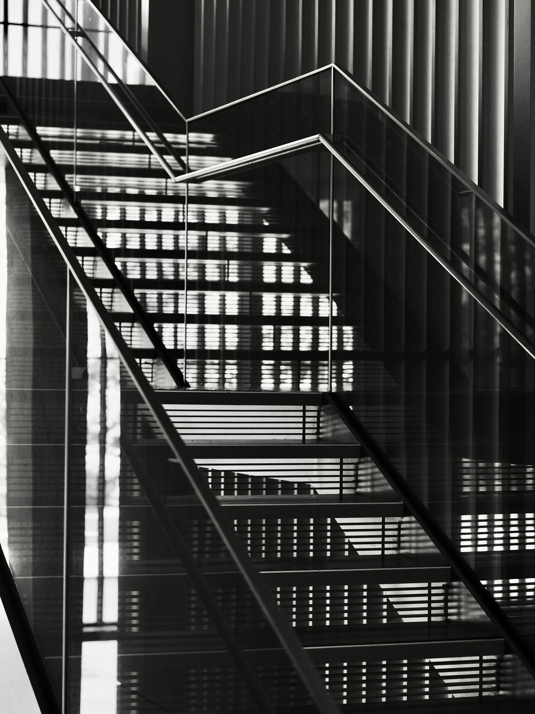 Escalier métallique droit à marches ajourées et garde-corps en verre